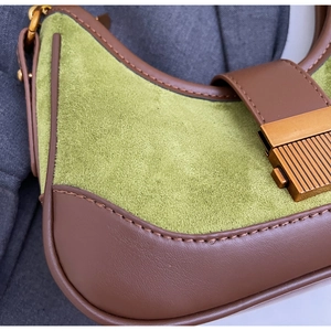 Detail of green suede shoulder bag with brown leather trim and retro metal buckle