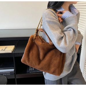 Detail of dark brown plush tote bag featuring golden metal chain and leather strap