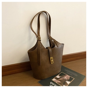 Close-up of brown leather bucket bag featuring a gold twist lock and adjustable straps