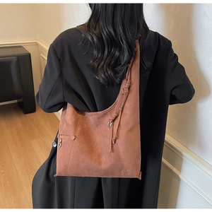 Detail of brown suede hobo bag featuring side drawstring ribbons and metal ring accents