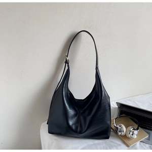 Detail of black large capacity hobo bag with soft faux leather texture and golden buckles