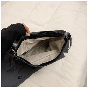 Vue détaillée de l'intérieur d'un sac cabas noir montrant la doublure à chevrons et la poche zippée