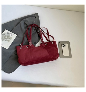 Detail view of burgundy velvet shoulder bag with wavy opening and silver metal hardware