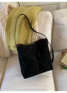 Detail einer schwarzen Wildleder-Beuteltasche mit braunem Innenfutter auf Sofa