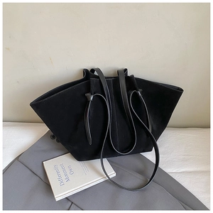 Detail of minimalist black tote bag showing texture contrast of suede and smooth leather