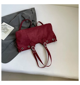 Detail of burgundy suede tote bag featuring metallic eyelets and adjustable buckle strap