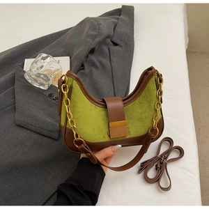 Detail of green faux suede underarm bag with brown leather trim and metal clasp