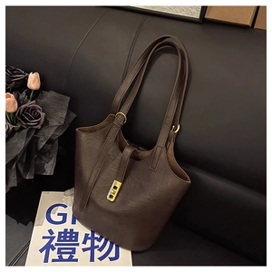 Close-up of brown faux leather bucket bag with gold rotating lock and adjustable strap