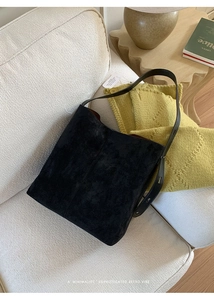 Detailansicht einer schwarzen Wildleder-Beuteltasche auf einem modernen Sofa