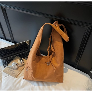Detailed view of the caramel suede tote bag with drawstring closure and metal ring detail