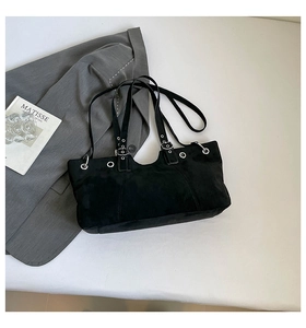 Detail of black suede tote bag featuring silver metal rings and adjustable buckle strap