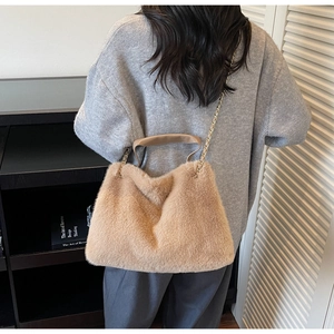 Detail view of the plush camel tote bag featuring golden metal chain and leather handle