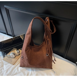 Detail shot of a large brown suede hobo bag showing texture, wide strap and knotted tassels