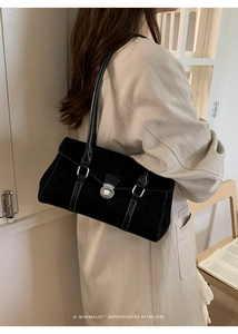 Close-up of a retro black suede underarm bag with silver lock and buckle details