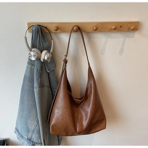 Macro detail of the brown soft leather hobo bag showing texture and durable shoulder strap