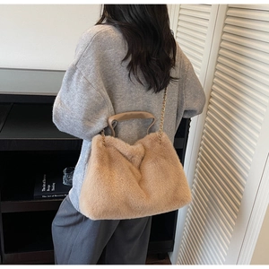 Model showing plush faux fur handbag in apricot with gold chain strap and top handle