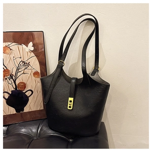 Close-up of black lychee-textured leather tote with elegant golden metal hardware buckle