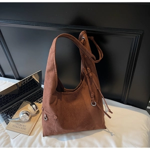 Detail of the brown suede tote bag featuring side drawstrings and silver metal ring accents