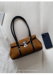 Detail of retro suede baguette bag with contrast leather trim and silver metal twist lock