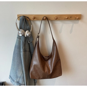 Detail of a large dark brown faux leather hobo bag with natural soft grain texture