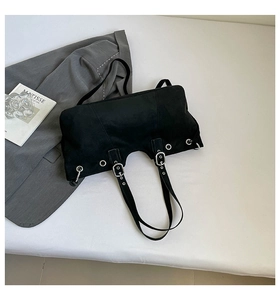 Detailed top view of black suede shoulder bag with silver eyelets and buckle strap