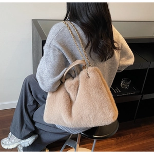 Detail of plush faux fur handbag with metal chain strap and leather handle on a model