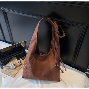 Macro shot of dark brown suede hobo bag detailing the tassel knot and metallic ring buckle