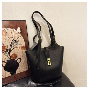 Close-up of black leather bucket bag featuring a polished gold rectangular metal twist lock