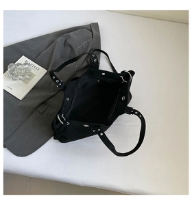 Close-up of black canvas tote bag featuring metallic silver eyelets and industrial design