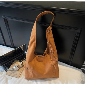 Detail of brown suede hobo bag featuring decorative knots on the shoulder strap