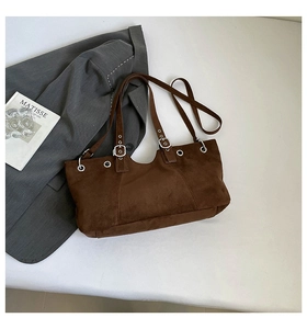 Close-up of dark brown suede shoulder bag with dual straps and metal eyelet details