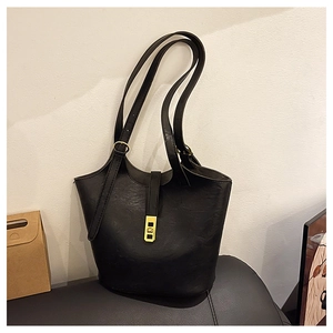 Detail of black tote bag featuring gold metal buckle and premium pebble leather texture