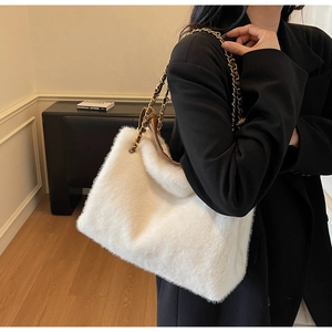 Detail of white plush tote bag with gold metal chain strap for winter fashion