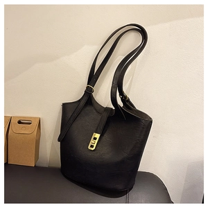 Close-up of black leather bucket bag featuring a polished gold metal buckle and dual straps