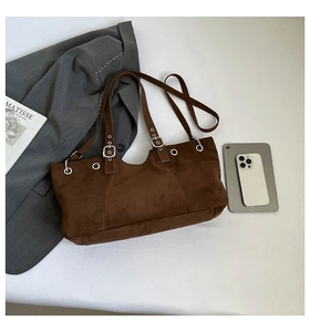 Close-up of brown suede crossbody bag with metallic studs and stylish silver buckles
