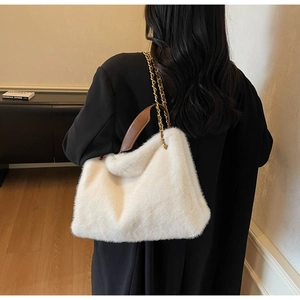 Detail of cream plush handbag with brown leather handle and gold chain on model