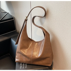 Detail view of large brown soft leather tote bag with vintage texture and brass buckle