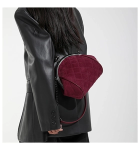 Close-up of wine red quilted velvet bag with vintage metal clasp and chain strap