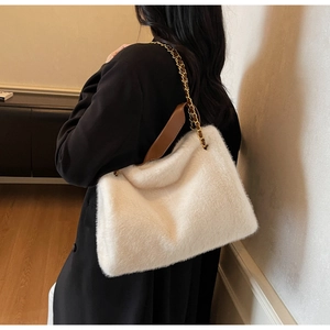 Close-up of white plush shoulder bag featuring soft faux fur texture and metal chain strap