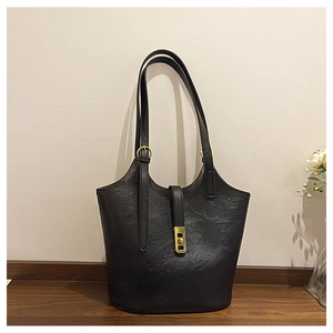 Detail of black large tote bag showing smooth leather texture and golden metal buckle