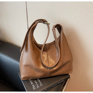 Detail shot of a dark camel hobo bag with vintage leather texture and wide strap