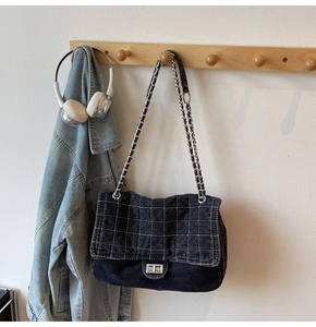 Détail du sac bandoulière en denim noir matelassé avec chaîne argentée et fermoir