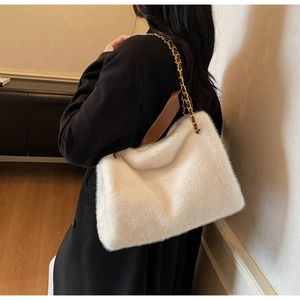 Detail of white plush shoulder bag with golden metal chain and brown leather strap
