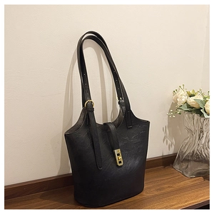 Macro detail of black vintage leather tote bag with gold metal latch and long shoulder strap