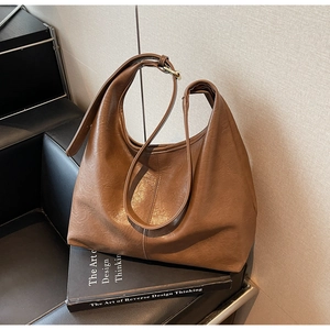 Detail view of the soft brown PU leather texture and adjustable strap on a large tote bag