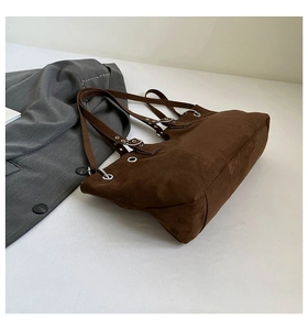 Detail of dark brown suede tote bag featuring silver eyelets and adjustable leather straps