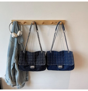 Détail de sacs en denim matelassé noir et bleu avec chaîne sur crochets en bois