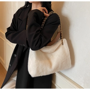 Detail view of off-white faux fur tote bag with brown leather strap and gold chain detail