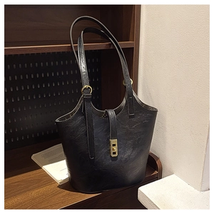 Detail of black vintage leather bucket bag with gold rotary lock on a wooden shelf