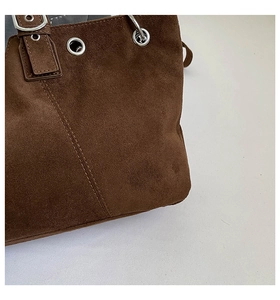 Detailed close-up of dark brown suede tote bag featuring silver eyelets and metal buckle